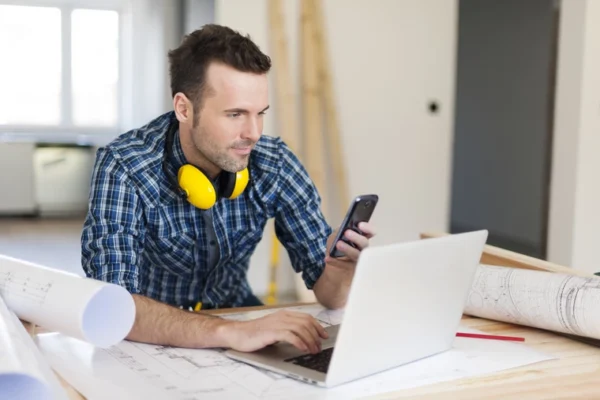 stock image of a man using his phone and computer